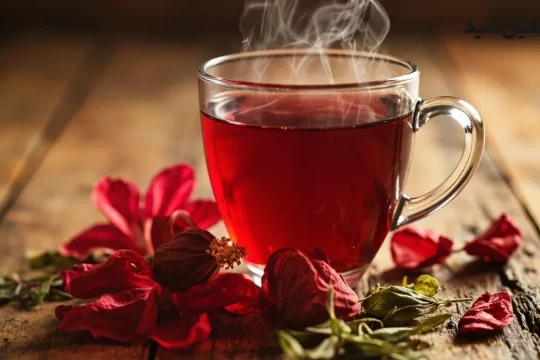 فنجان چای ترش در کنار گل‌های خشک هیبیسکوس و برگ چای