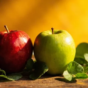 سیب قرمز و سبز تازه با برگ‌های سبز، نماد سلامت و تغذیه سالم